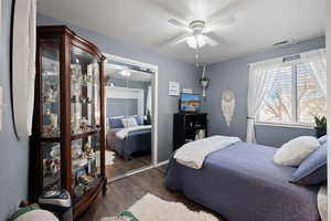 Guest Bedroom featuring ceiling fan, dark wood-style floors, murphy bed and a closet