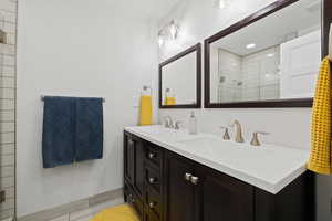 Primary Bathroom featuring double vanity, tile flooring, and tiled shower