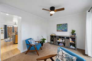 Sitting room featuring ceiling fan, light carpet, and crown molding