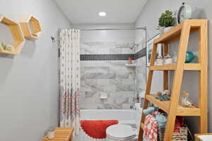 Bathroom featuring tiled shower / tub combo and toilet