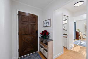 Entrance foyer with crown molding and light hardwood floors