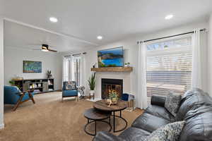 Living room featuring carpet, ceiling fan, and a fireplace and sliding glass door to back patio