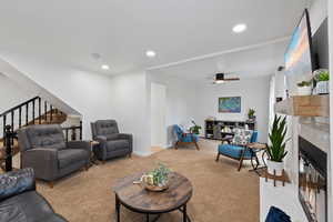 Carpeted living room with crown molding and ceiling fan