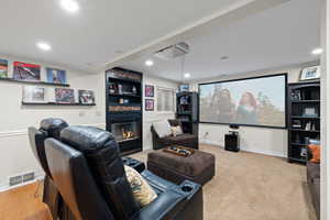 Living room with light carpet floors, projector and screen, and large fireplace