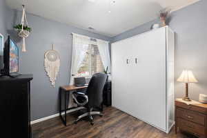 Guest Bedroom featuring ceiling fan, dark wood-style floors, murphy bed storage cabinet, and desk