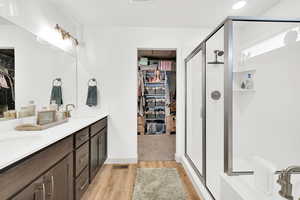 Bathroom featuring hardwood / wood-style flooring, vanity, and a shower with door