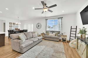 Living room featuring light hardwood / wood-style flooring and ceiling fan with notable chandelier