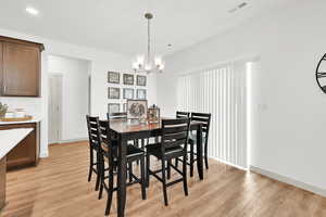 Dining area featuring light wood-type flooring and an inviting chandelier