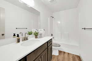 Full bathroom featuring hardwood / wood-style floors, vanity, shower / bath combination, and toilet