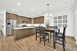 Kitchen with dark brown cabinetry, hanging light fixtures, stainless steel appliances, and an inviting chandelier