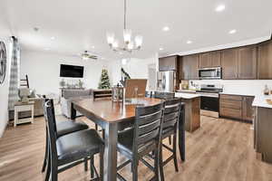 Dining space with ceiling fan with notable chandelier and light hardwood / wood-style floors