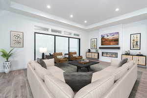 Living room with a fireplace, hardwood / wood-style floors, and a tray ceiling