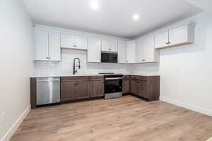 Kitchen featuring white cabinetry, sink, light hardwood / wood-style floors, and appliances with stainless steel finishes