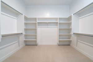 Spacious closet featuring light colored carpet