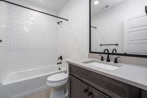 Full bathroom featuring toilet, vanity, and tiled shower / bath