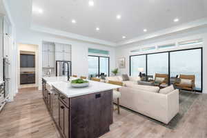 Kitchen with a breakfast bar area, light hardwood / wood-style flooring, an island with sink, and dark brown cabinets