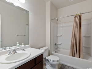 Full bathroom with tile patterned flooring, shower / bath combination with curtain, toilet, and vanity