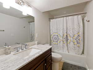 Full bathroom featuring vanity, tile patterned flooring, toilet, a textured ceiling, and shower / tub combo