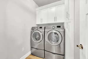 Washroom featuring cabinets, separate washer and dryer, and light wood-type flooring