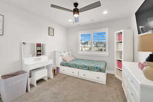 Carpeted bedroom featuring ceiling fan