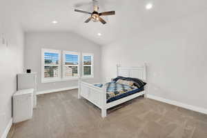 Bedroom featuring light colored carpet, vaulted ceiling, and ceiling fan