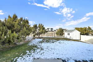 Yard covered in snow featuring a shed