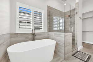 Bathroom featuring tile patterned floors, tile walls, and plus walk in shower