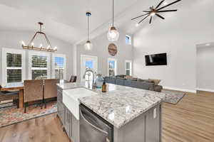 Kitchen featuring plenty of natural light, dishwasher, a center island with sink, and light wood-type flooring