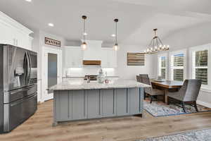 Kitchen featuring a center island with sink, white cabinets, light hardwood / wood-style flooring, and appliances with stainless steel finishes