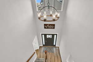 Foyer entrance with a high ceiling, hardwood / wood-style flooring, and an inviting chandelier