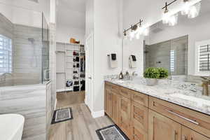 Bathroom featuring vanity, a wealth of natural light, plus walk in shower, and wood-type flooring