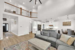 Living room featuring a notable chandelier, sink, a high ceiling, and light hardwood / wood-style flooring