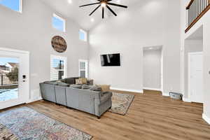 Living room featuring ceiling fan, wood-type flooring, and high vaulted ceiling