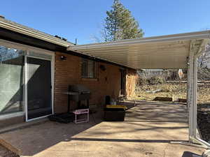 View of patio with a carport, concrete driveway, and a grill