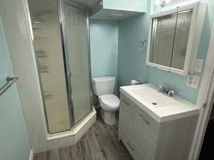 Bathroom with wood finish floors, visible vents, toilet, a stall shower, and vanity