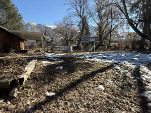 Snowy yard featuring a carport, a mountain view, and a playground