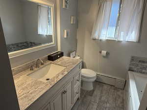 Bathroom with a bathing tub, toilet, a baseboard heating unit, vanity, and wood tiled floor