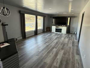 Unfurnished living room featuring baseboard heating, a fireplace, and wood finished floors