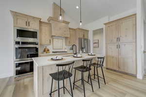 Kitchen featuring stainless steel appliances, hanging light fixtures, and light brown cabinetry