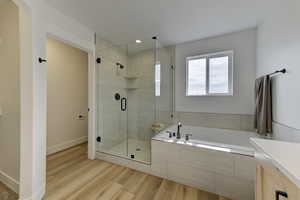Primary Bathroom featuring vanity, wood-type flooring, and separate shower and tub