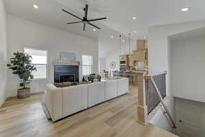 Living room featuring ceiling fan, high vaulted ceiling, and light hardwood / wood-style floors