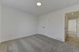 Unfurnished bedroom featuring light carpet and a closet