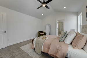 Primary Bedroom featuring carpet floors, ensuite bathroom, ceiling fan, and vaulted ceiling