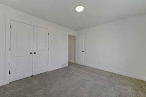 Unfurnished bedroom featuring light colored carpet and a closet