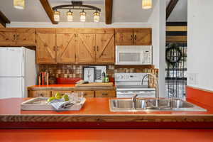 Kitchen with backsplash, sink, beam ceiling, and white appliances