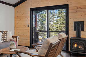 Living room featuring a wood stove, wooden walls, a healthy amount of sunlight, and lofted ceiling