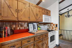 Kitchen with an inviting chandelier, tasteful backsplash, dark hardwood / wood-style floors, white appliances, and ornamental molding