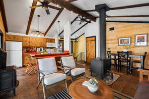 Living room featuring hardwood / wood-style floors, vaulted ceiling with beams, and a wood stove