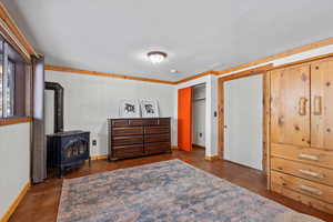 Bedroom with a wood stove, crown molding, a closet, and a textured ceiling