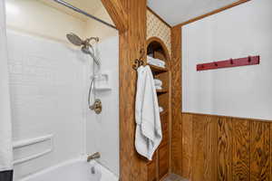 Bathroom featuring wood walls, a textured ceiling, and tiled shower / bath